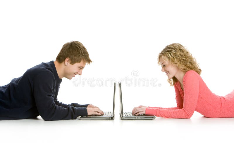 Attractive teenagers lying down using lap tops isolated on white background. Attractive teenagers lying down using lap tops isolated on white background