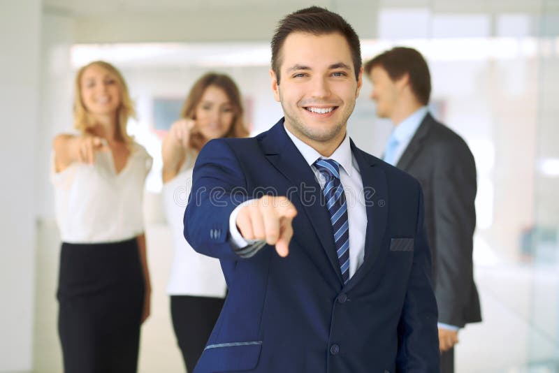 Οι επιτυχείς νέοι επιχειρηματίες που παρουσιάζουν αντίχειρες υπογράφουν επάνω στεμένος στο γραφείο πιό interier στοκ φωτογραφία
