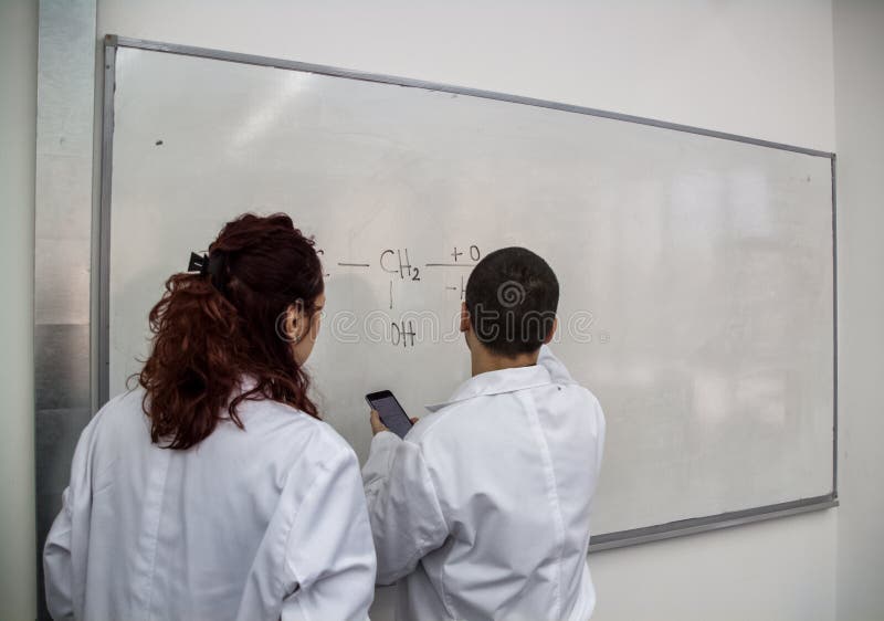 Οι νέοι γιατροί είναι τυπωμένοι μερικά χημικά στοιχεία σε έναν άσπρο κάπρο στοκ φωτογραφίες Οι νέοι γιατροί είναι τυπωμένοι μερικά χημικά στοιχεία σε έναν άσπρο κάπρο στοκ φωτογραφίες