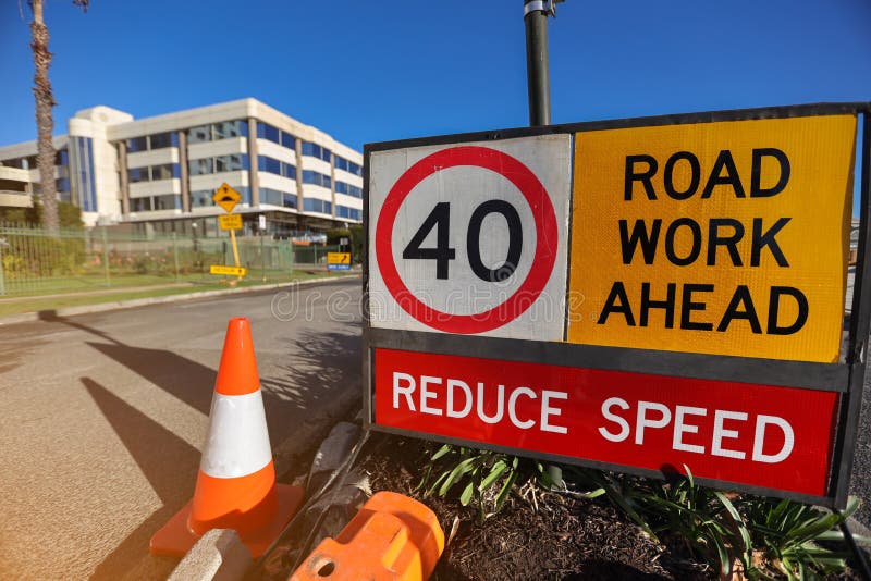 Yellow board with black whiting road work ahead reduce speed 40 KM/H speed limit zone safety warning sign applying on public busy residential areas where construction work repairing upgrading Sydney. Yellow board with black whiting road work ahead reduce speed 40 KM/H speed limit zone safety warning sign applying on public busy residential areas where construction work repairing upgrading Sydney