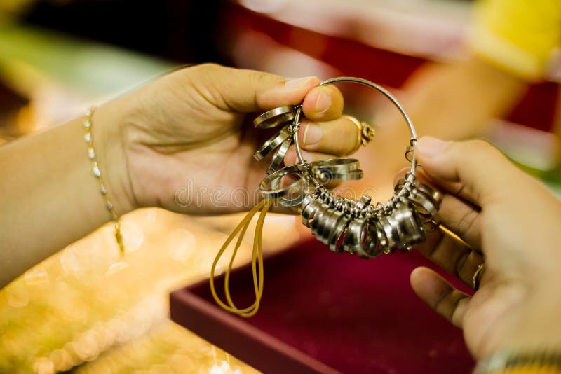 Women customers are measuring finger size with a ring of size to choose to buy gold van jewelry in gold shop. Yaowarat gold shop, Thailand. Women customers are measuring finger size with a ring of size to choose to buy gold van jewelry in gold shop. Yaowarat gold shop, Thailand