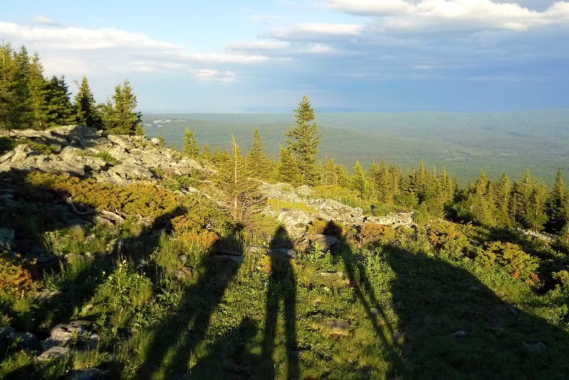 Travel to Ural mountains, Russia. The shadows with the people on the view on the mountains, forest and cloudy sky. Travel to Ural mountains, Russia. The shadows with the people on the view on the mountains, forest and cloudy sky.