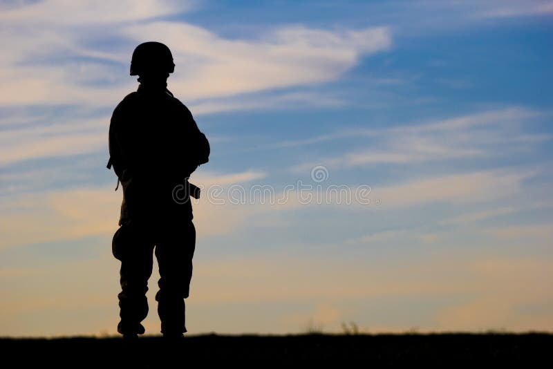A lone soldiers silhouette breaks the horizon against a setting sun. A lone soldiers silhouette breaks the horizon against a setting sun.