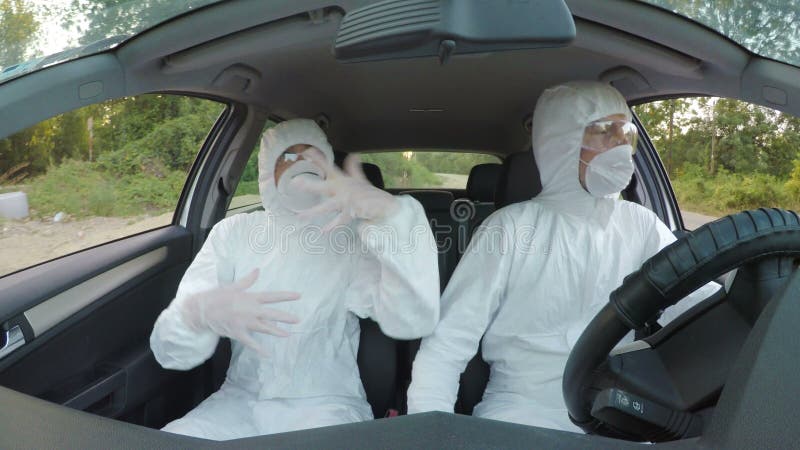 Οι τρελλοί τεχνικοί επιστημόνων biohazard στο hazmat ταιριάζουν το χορό και την οδήγηση για να εργαστούν σε ένα αυτοκίνητο -