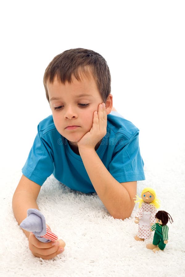 Sad boy thinking of his separated family playing with figurines on the floor - divorce concept, isolated. Sad boy thinking of his separated family playing with figurines on the floor - divorce concept, isolated
