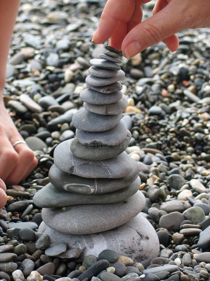 Mom and daughter constructs a tower of rocks. Mom and daughter constructs a tower of rocks