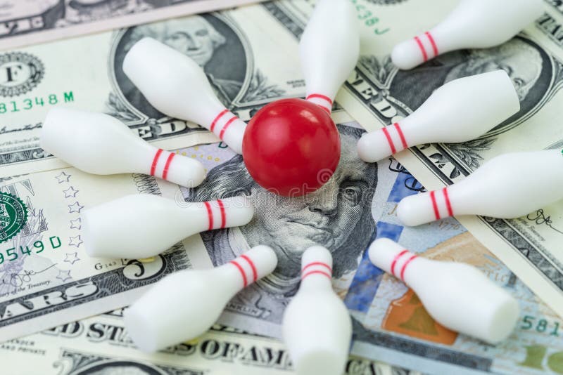 Financial success target concept, red winning bowling strike ball surround with knocked down pins on pile of US dollar banknotes money, goals on investment or profit in stock market metaphor. Financial success target concept, red winning bowling strike ball surround with knocked down pins on pile of US dollar banknotes money, goals on investment or profit in stock market metaphor.