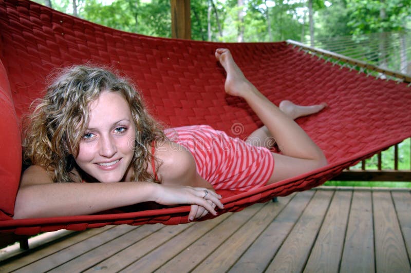 A pretty girl lounging in a hammock on a porch. A pretty girl lounging in a hammock on a porch