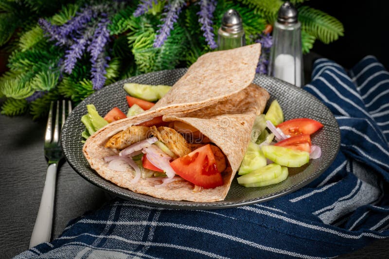Wholegrain tortilla wraps with vegetables and chicken on a plate on the table. Wholegrain tortilla wraps with vegetables and chicken on a plate on the table