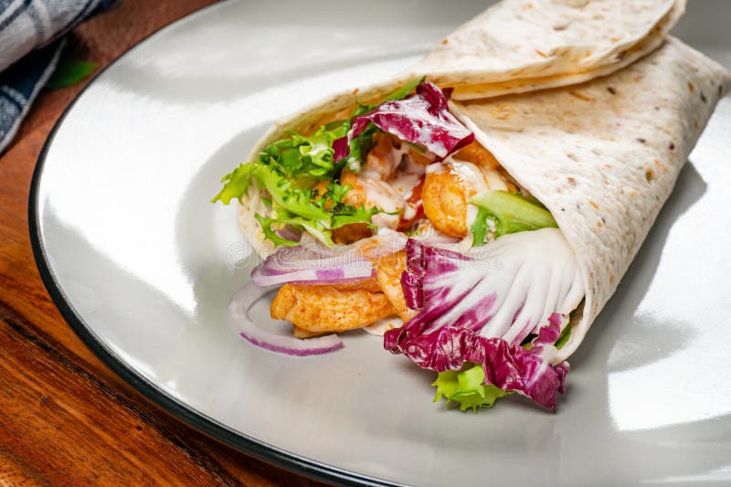 Wholegrain tortilla wraps with vegetables and chicken on a plate on the table. Wholegrain tortilla wraps with vegetables and chicken on a plate on the table