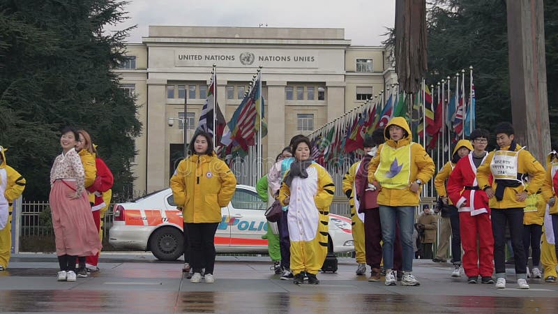 Ομάδα ασιατικών νέων που χορεύουν κοντά στο γραφείο των Η.Ε, αστυνομία που φρουρεί τη δημόσια τάξη
