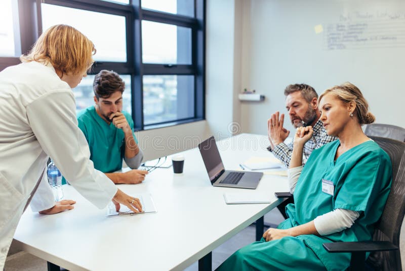 Group of medical professionals brainstorming in a meeting. Team of healthcare workers discussing in boardroom, with female doctor presenting her plan. Group of medical professionals brainstorming in a meeting. Team of healthcare workers discussing in boardroom, with female doctor presenting her plan.