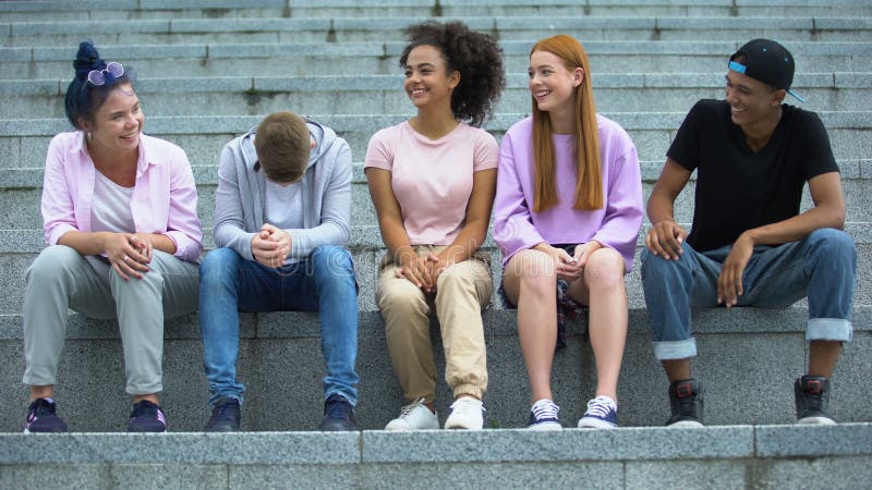 Ομάδα πολυεθνικών νέων που κάθονται στις σκάλες της ακαδημίας, χρόνος αναψυχής
