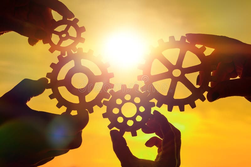 Team of people with gears in hands on sunset background. business. interaction. Team of people with gears in hands on sunset background. business. interaction.