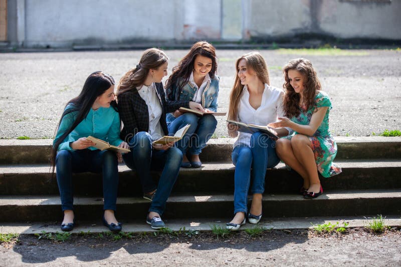 ομάδα φοιτητών που κάθεται με βιβλία στην αυλή του πανεπιστημίου
