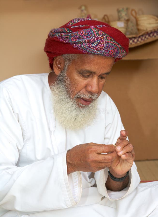 MUSCAT, OMAN - FEBRUARY 1, 2008: A bearded Omani craftsman, wearing a traditional muzzar (headcloth), at work in Muscat, in the Sultanate of Oman. MUSCAT, OMAN - FEBRUARY 1, 2008: A bearded Omani craftsman, wearing a traditional muzzar (headcloth), at work in Muscat, in the Sultanate of Oman.