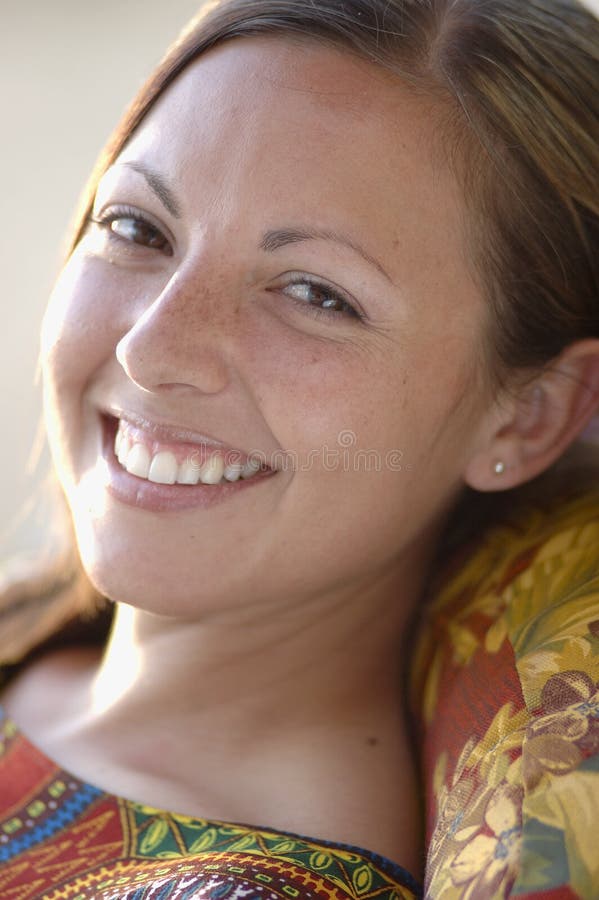 Young woman smiling. Close up portrait while she lounges wearing an ethnic top. Young woman smiling. Close up portrait while she lounges wearing an ethnic top.
