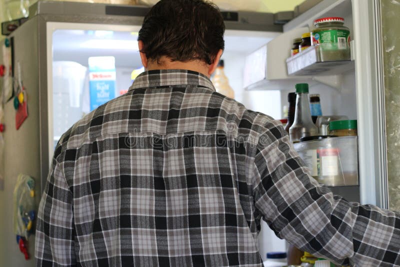 Οπισθοσκόπος ενός ταραγμένου νεαρού άνδρα που εξετάζει τα τρόφιμα στο ψυγείο στοκ φωτογραφίες Οπισθοσκόπος ενός ταραγμένου νεαρού άνδρα που εξετάζει τα τρόφιμα στο ψυγείο στοκ φωτογραφίες