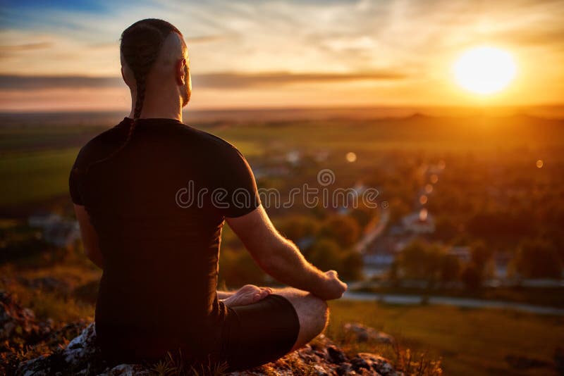 Οπισθοσκόπος του ατόμου η meditating γιόγκα στο λωτό θέτει στο βράχο στο ηλιοβασίλεμα στοκ φωτογραφία Οπισθοσκόπος του ατόμου η meditating γιόγκα στο λωτό θέτει στο βράχο στο ηλιοβασίλεμα στοκ φωτογραφία