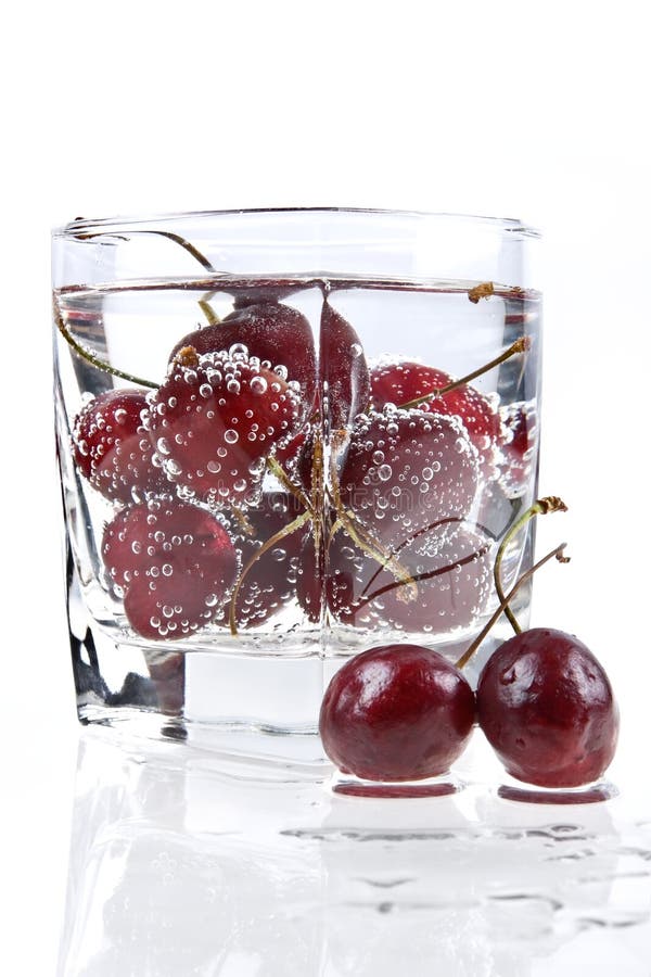 Glass with mineral water and sweet cherry makes thirsty. Glass with mineral water and sweet cherry makes thirsty