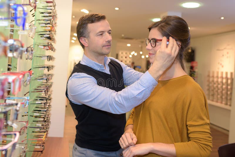 Οφθαλμολόγος και όμορφο θηλυκό brunette που επιλέγουν τα γυαλιά στο κατάστημα οπτικής στοκ φωτογραφίες με δικαίωμα ελεύθερης χρήσης