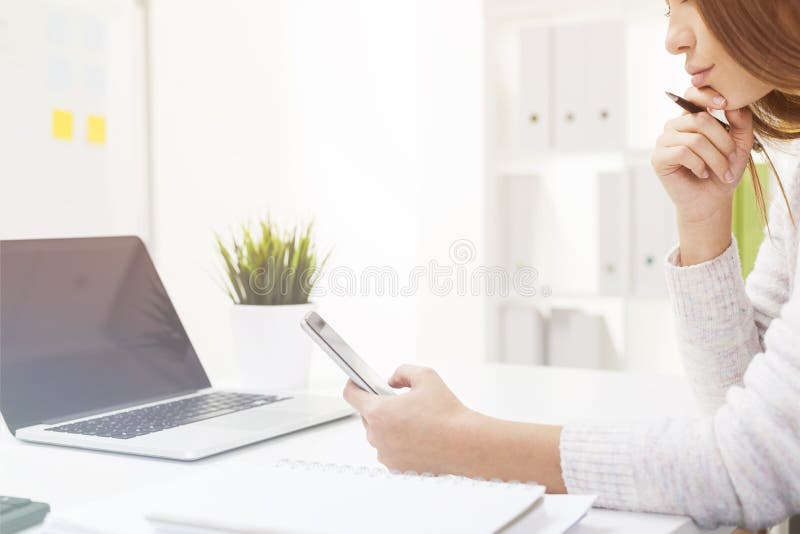 Πλάγια όψη της επιχειρηματία που εξετάζει το smartphone της σε ένα λευκό στοκ φωτογραφίες