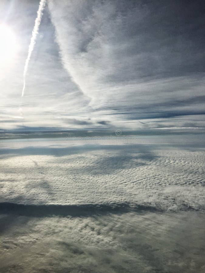 Flying between layers of cloud. Jet contrail casts a shadow on the lower layers. Includes cirrus, cirrocumulus, and altocumulus cloud types. Flying between layers of cloud. Jet contrail casts a shadow on the lower layers. Includes cirrus, cirrocumulus, and altocumulus cloud types.