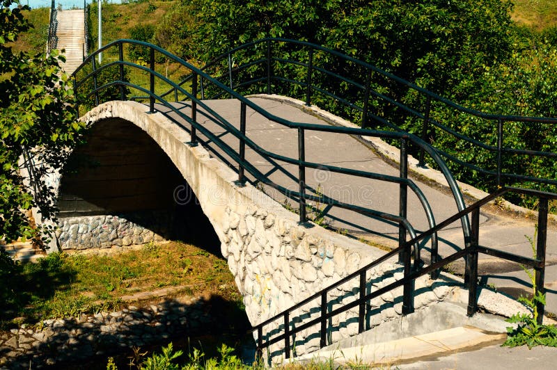 Πέτρινη γέφυρα πέρα από λίγο ποταμό στο πάρκο πόλεων στοκ φωτογραφίες με δικαίωμα ελεύθερης χρήσης Πέτρινη γέφυρα πέρα από λίγο ποταμό στο πάρκο πόλεων στοκ φωτογραφίες με δικαίωμα ελεύθερης χρήσης