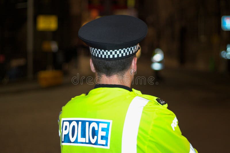 Policeman standing on the street, back, police uniform. Night time. Policeman standing on the street, back, police uniform. Night time