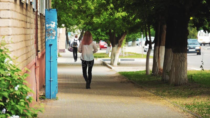 Πίσω άποψη του περπατήματος κοριτσιών μόνο στην παλαιά πόλη Γυναίκα Brunette που περνά από την οδό απόθεμα βίντεο
