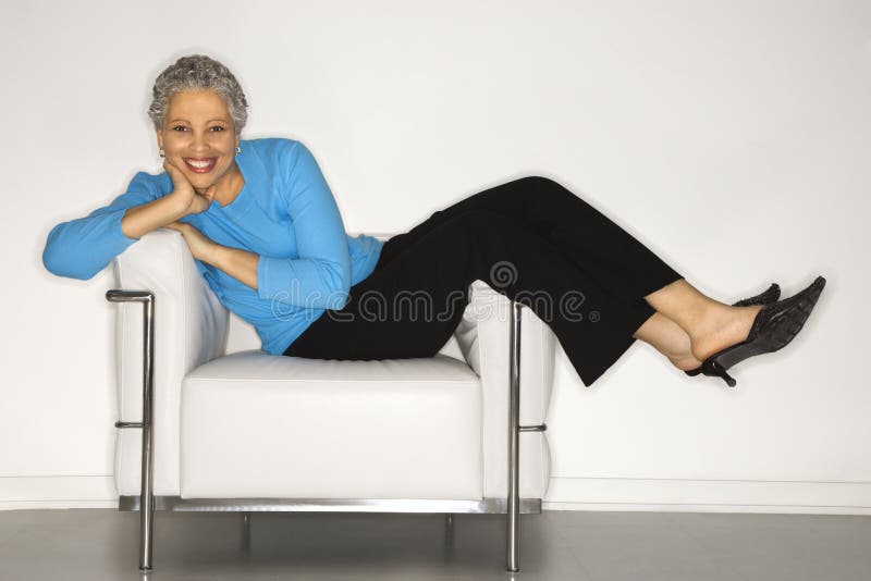 African American mature adult female lying back on chair. African American mature adult female lying back on chair.