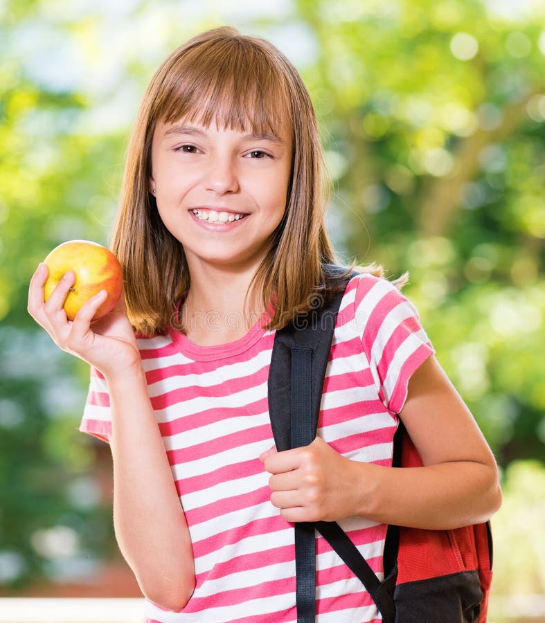Outdoor portrait of happy girl 10-11 year old with apple and backpack. Back to school concept. Outdoor portrait of happy girl 10-11 year old with apple and backpack. Back to school concept.