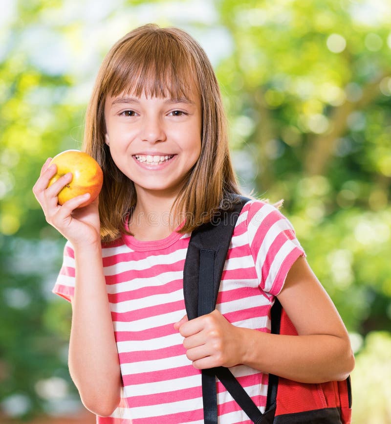 Outdoor portrait of happy girl 10-11 year old with apple and backpack. Back to school concept. Outdoor portrait of happy girl 10-11 year old with apple and backpack. Back to school concept.