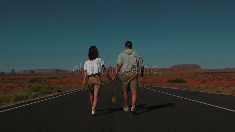 πίσω όψη ένα ρομαντικό ζευγάρι περπατά μαζί κρατώντας χέρια προς την επική άσπρη επιφάνεια στη μέση της αλατώδους ερήμου της γιούτ