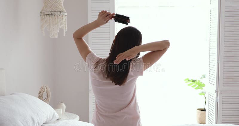 πίσω όψη νεαρή μελαχρινή γυναίκα που κάνει ρουτίνα στο στυλ των μαλλιών.