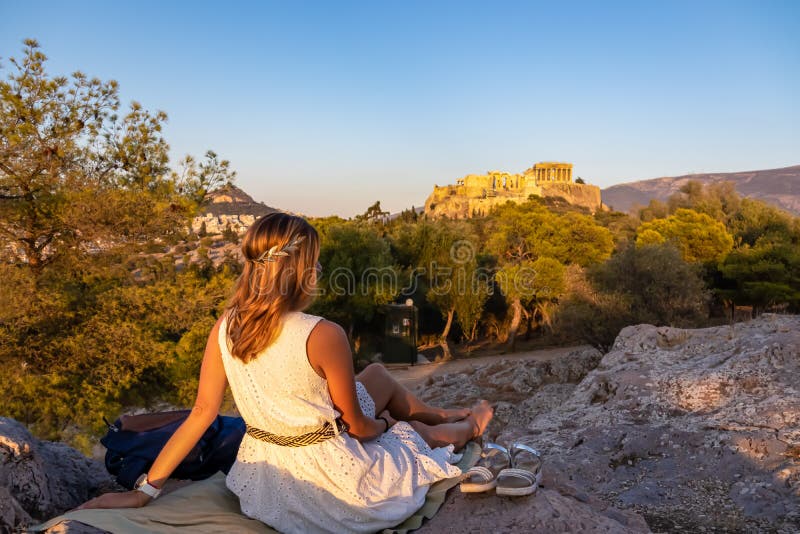 πίσω όψη της αθήνας τουρίστρια που κοιτάζει τον παρθενώνα της ακρόπολης της αθήνας κατά τη διάρκεια του ηλιοβασιλέματος από το pny στοκ φωτογραφία