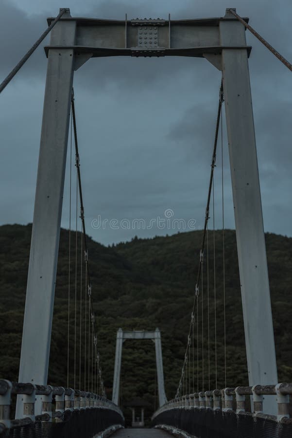 Παλαιά σκοτεινή γέφυρα τη νεφελώδη ημέρα. Μια παλαιά σκοτεινή και μειωμένη γέφυρα σε ένα βουνό στην επαρχία της Ιαπωνίας μια συννεφιάζω ημέρα