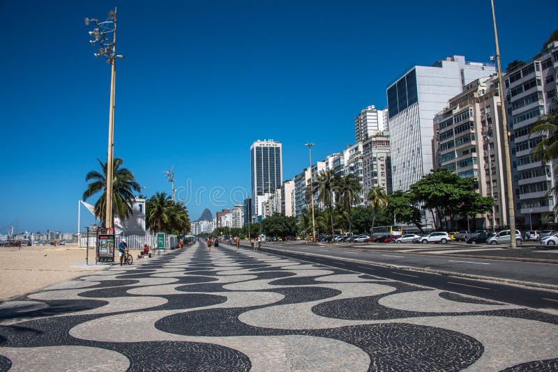 Παγκόσμιος διάσημος περίπατος Copacabana με τους φοίνικες, γραπτό μωσαϊκό του πορτογαλικού πεζοδρομίου στο Ρίο ντε Τζανέιρο στοκ φωτογραφία με δικαίωμα ελεύθερης χρήσης Παγκόσμιος διάσημος περίπατος Copacabana με τους φοίνικες, γραπτό μωσαϊκό του πορτογαλικού πεζοδρομίου στο Ρίο ντε Τζανέιρο στοκ φωτογραφία με δικαίωμα ελεύθερης χρήσης