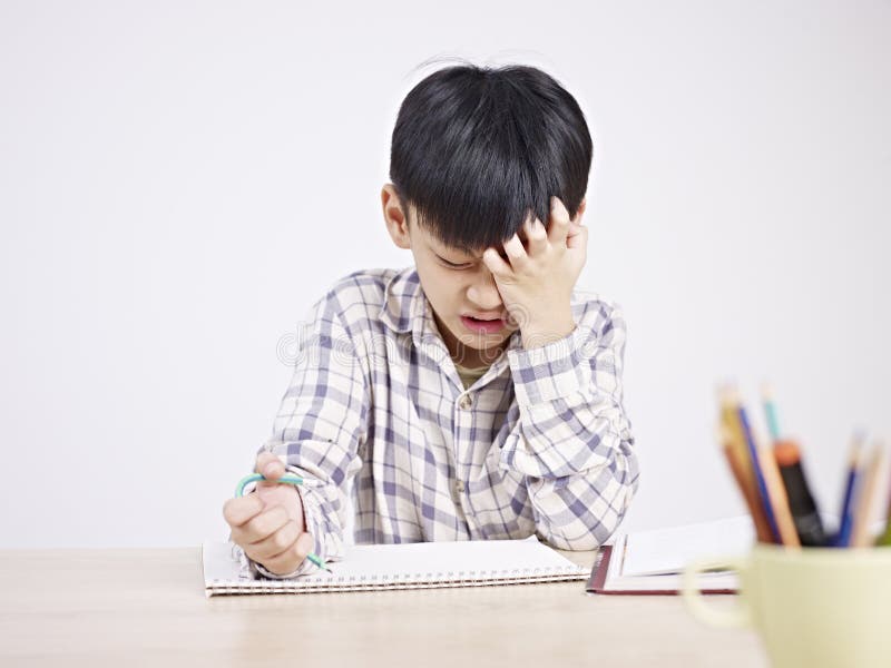 10 year-old asian elementary schoolboy appears to be frustrated while doing homework. 10 year-old asian elementary schoolboy appears to be frustrated while doing homework.