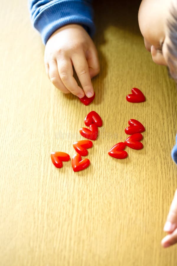 Child boy align the lot red hearts motifs on wooden background.boy`s hand. copy space. Child boy align the lot red hearts motifs on wooden background.boy`s hand. copy space