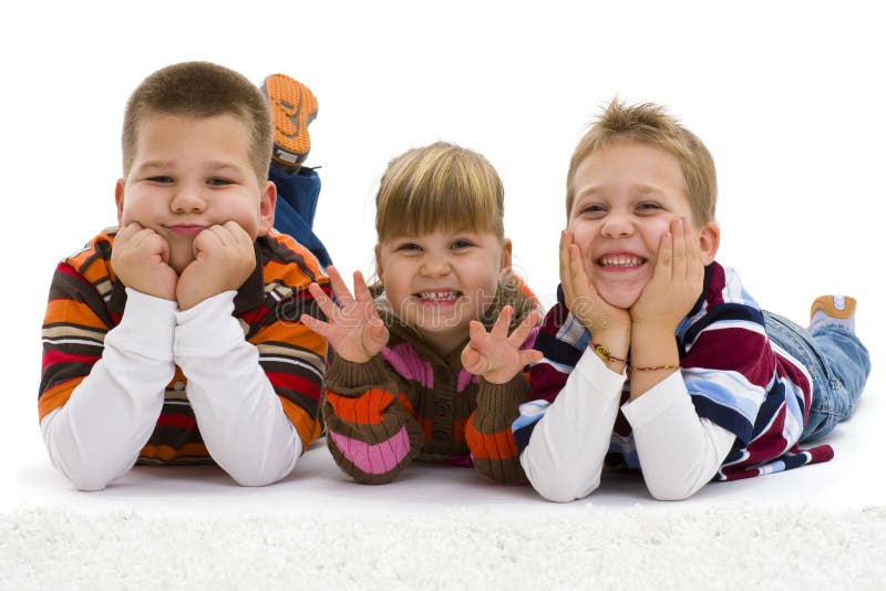 Group of 3 happy children lying on floor, wearing colorful, striped pullover and t-shirt, laughing. Isolated on white background. Group of 3 happy children lying on floor, wearing colorful, striped pullover and t-shirt, laughing. Isolated on white background.