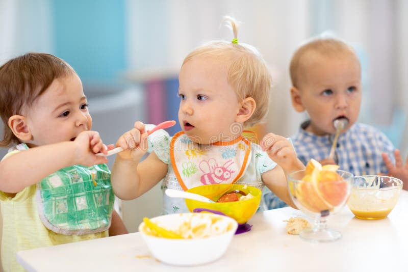 Παιδιά βρέφη που τρώνε υγιεινό φαγητό στο νηπιαγωγείο ή στον παιδικό σταθμό