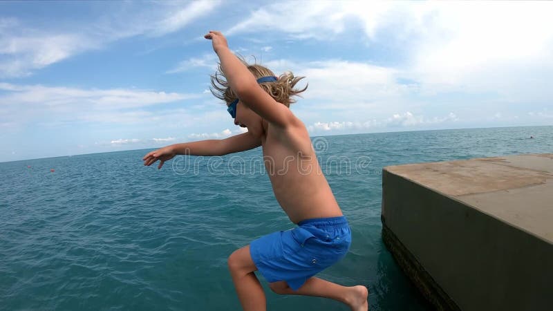 Παιδιά που τρέχουν και πηδούν από την προβλήτα σε θαλασσινό νερό