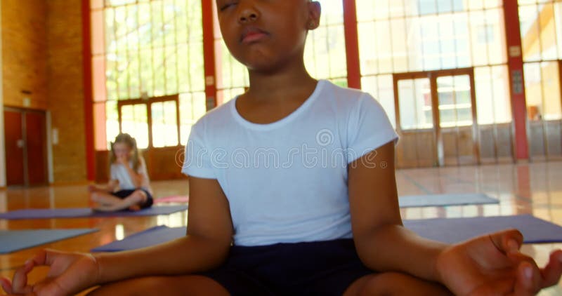Παιδιά σχολείου που εκτελούν τη γιόγκα σε ένα χαλί άσκησης στο σχολείο 4k
