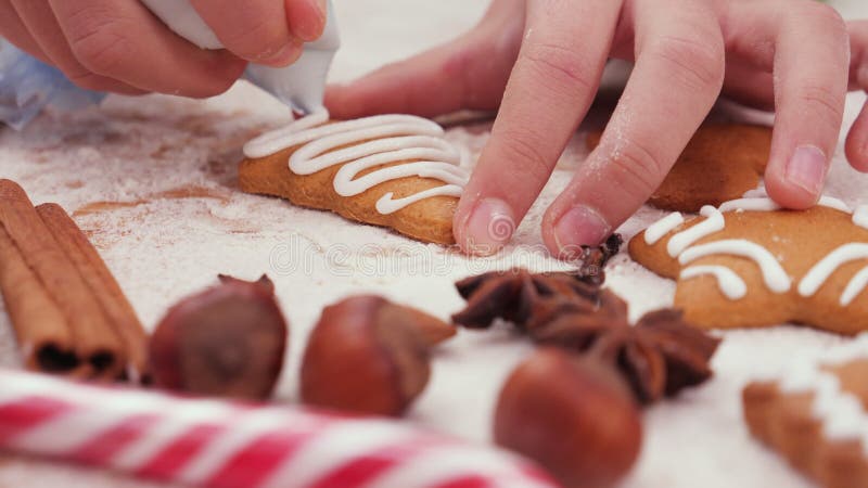 παιδικά χέρια που διακοσμούν ένα χριστουγεννιάτικο μπισκότο σε σχήμα πεύκου