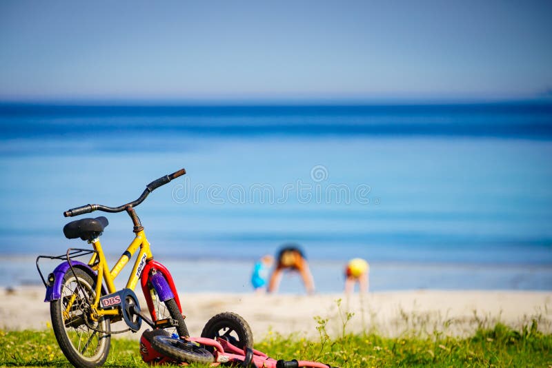 GIMSOYA, NORWAY - JULY 17, 2018: Child bikes with safety helmet parked on beach seashore in summer. Lofoten archipelago Norway. Holidays and adventure. GIMSOYA, NORWAY - JULY 17, 2018: Child bikes with safety helmet parked on beach seashore in summer. Lofoten archipelago Norway. Holidays and adventure