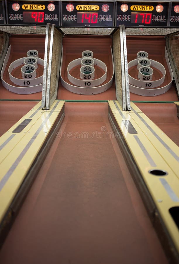 A midway carnival Skeeball bowling amusement game at an arcade in which the player rolls a ball and tries to win tickets. A midway carnival Skeeball bowling amusement game at an arcade in which the player rolls a ball and tries to win tickets.