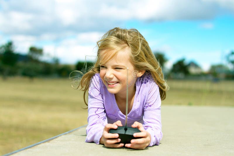 A little girl lying down and enjoying playing with a remote controlled toy. A little girl lying down and enjoying playing with a remote controlled toy.