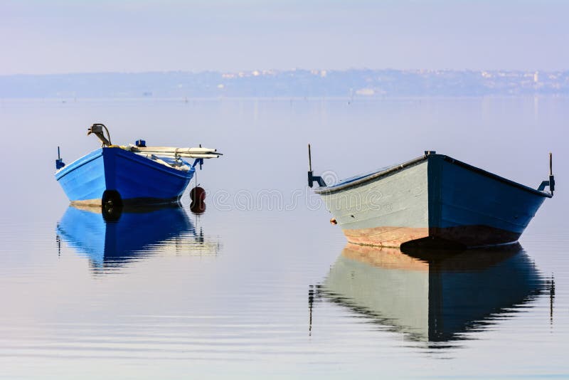 Παλαιά αλιευτικά σκάφη με τα φωτεινά χρώματα στην αυγή στη λίμνη στοκ φωτογραφία με δικαίωμα ελεύθερης χρήσης Παλαιά αλιευτικά σκάφη με τα φωτεινά χρώματα στην αυγή στη λίμνη στοκ φωτογραφία με δικαίωμα ελεύθερης χρήσης