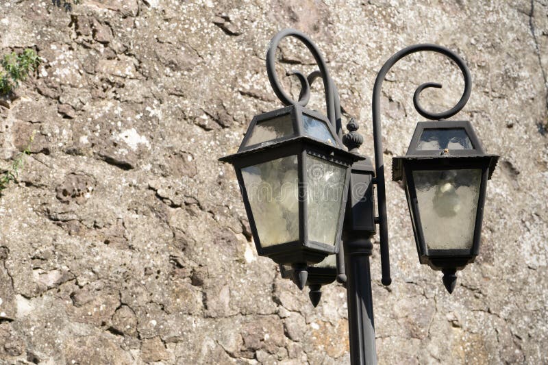 παλαιά πολύχρωμα γυάλινα φανάρια της οδού και διακοσμήσεις σιδήρου από μαύρο καφέ φόντο σε ανοιχτό καφέ πέτρινο φόντο στον ήλιο στοκ φωτογραφία με δικαίωμα ελεύθερης χρήσης